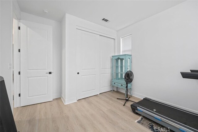 exercise area with light wood-type flooring and baseboards