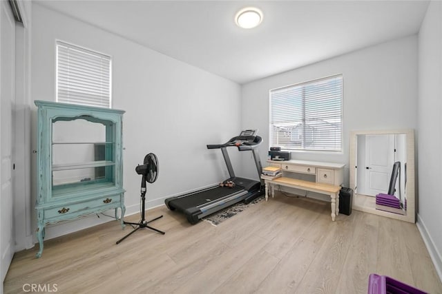 exercise room with light wood-type flooring and baseboards