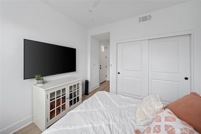 bedroom featuring baseboards, wood finished floors, a closet, and ceiling fan