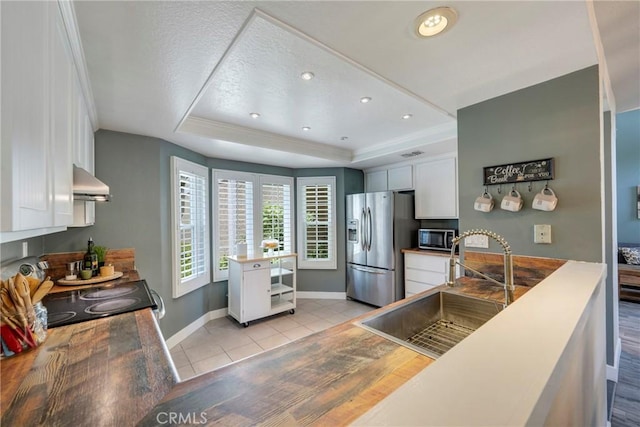 6060 E Summit Ct, Anaheim Hills, CA 92807 - kitchen with stainless steel appliances, a raised ceiling, exhaust hood, white cabinetry, and baseboards