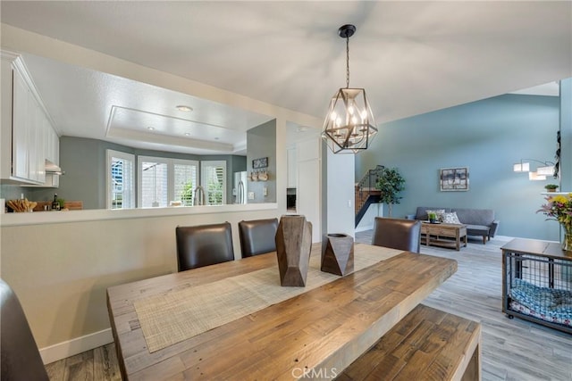 6060 E Summit Ct, Anaheim Hills, CA 92807 - dining space featuring a tray ceiling, a chandelier, light wood finished floors, baseboards, and stairway
