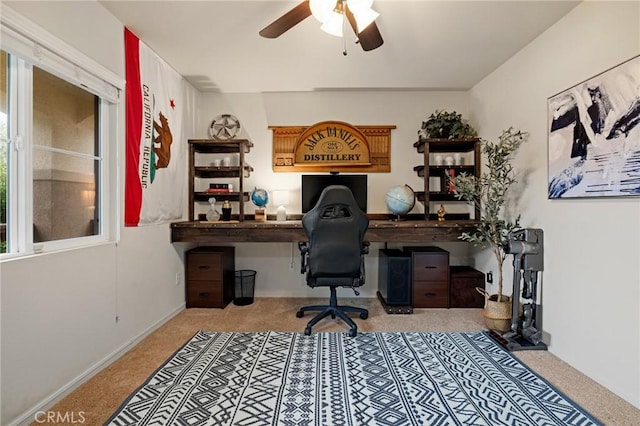 office area with carpet, built in desk, ceiling fan, and baseboards