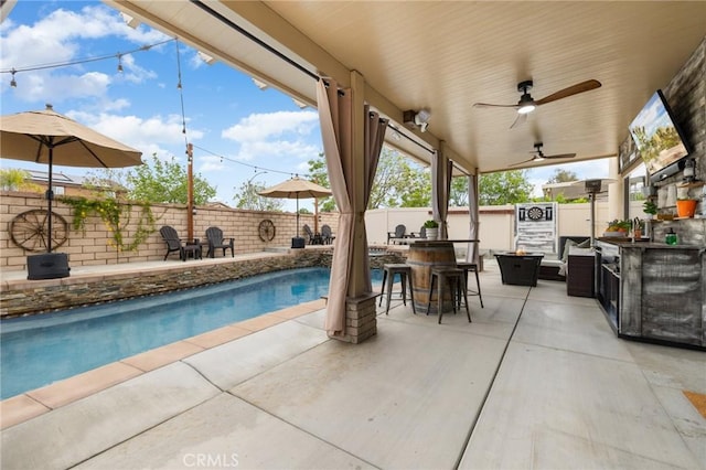view of swimming pool featuring a fenced backyard, a patio, and exterior kitchen