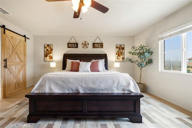 bedroom with a barn door, ceiling fan, and baseboards