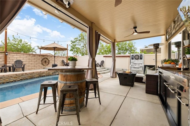 view of patio / terrace featuring an outdoor fire pit, a fenced backyard, and a ceiling fan