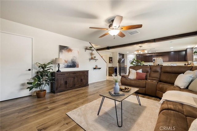 living room with light wood-style floors, ceiling fan, and beam ceiling