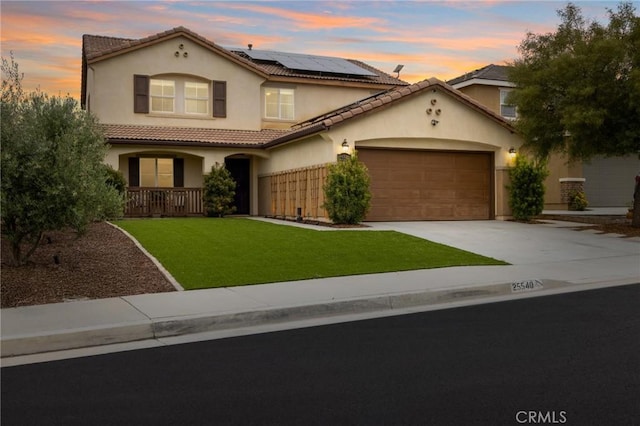 mediterranean / spanish-style house featuring stucco siding, driveway, roof mounted solar panels, an attached garage, and a tiled roof