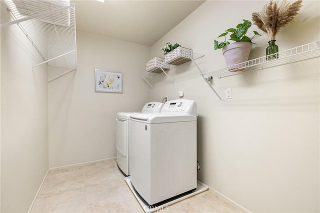 washroom with washing machine and clothes dryer and baseboards