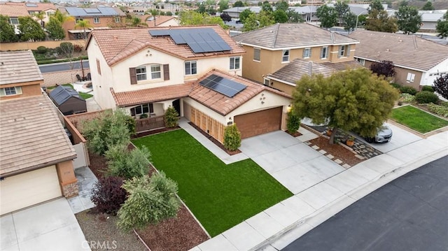 view of front facade with solar panels, a residential view, a tile roof, concrete driveway, and stucco siding