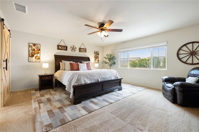 bedroom with a barn door, light carpet, baseboards, and ceiling fan