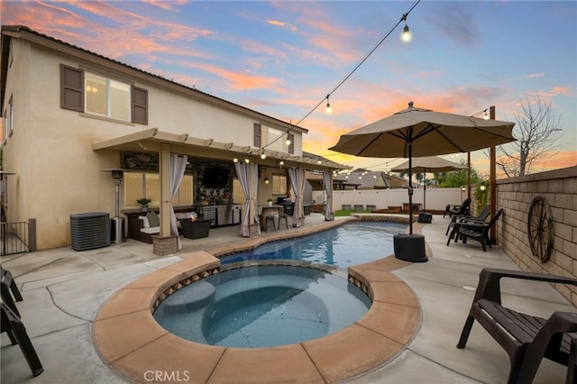 pool at dusk with a patio area, a fenced backyard, central AC, and a pool with connected hot tub