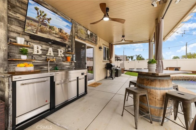 view of patio / terrace featuring a fenced backyard, an outdoor kitchen, exterior bar, and area for grilling
