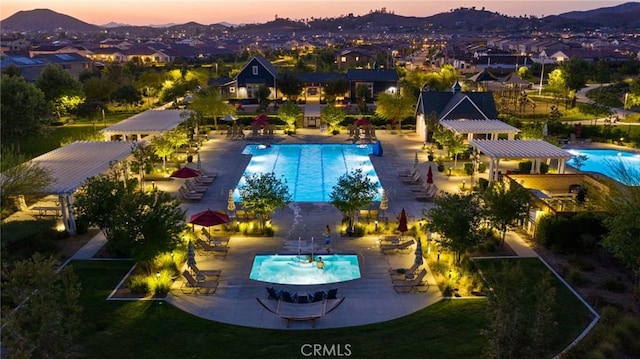 community pool with a residential view, a patio, a mountain view, and a lawn