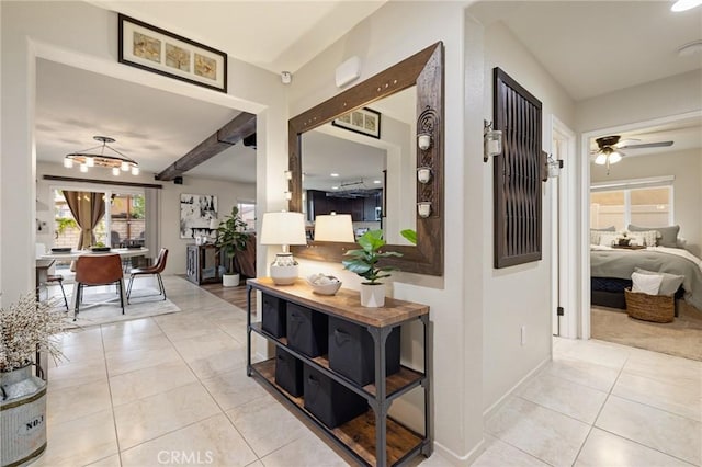 hall featuring light tile patterned floors, baseboards, and beam ceiling
