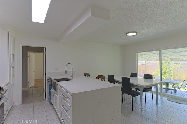 12406 Benson Ave, Chino, CA 91710 - kitchen featuring a sink, light tile patterned floors, white cabinetry, light stone counters, and a textured ceiling