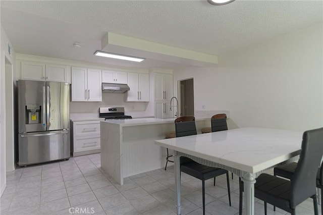 12406 Benson Ave, Chino, CA 91710 - kitchen with appliances with stainless steel finishes, under cabinet range hood, white cabinetry, a textured ceiling, and a breakfast bar