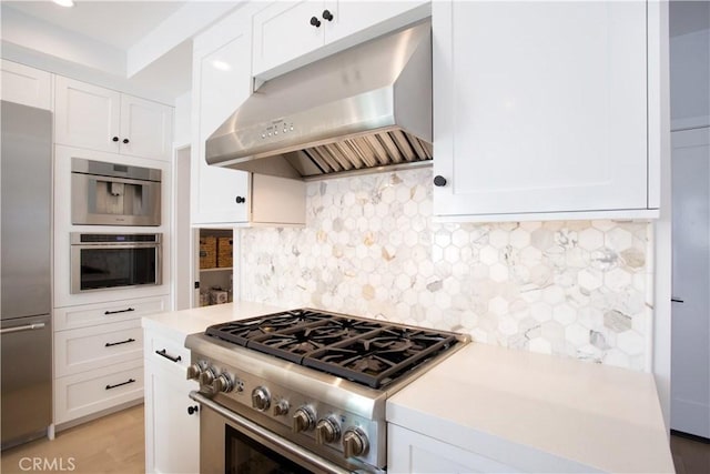 kitchen with high end appliances, under cabinet range hood, light countertops, and white cabinetry
