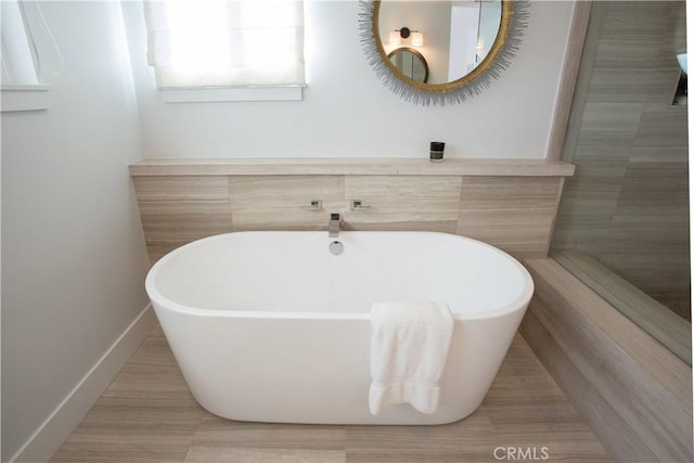 full bath with a freestanding bath and baseboards