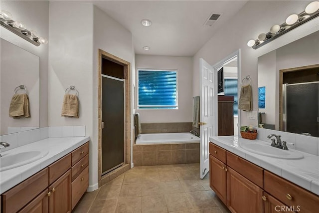 full bathroom with a shower stall, tile patterned floors, two vanities, and a garden tub