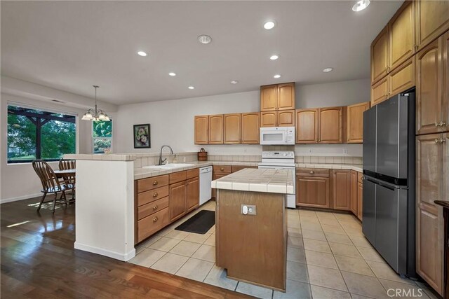 kitchen with white appliances, tile counters, a center island, a peninsula, and recessed lighting