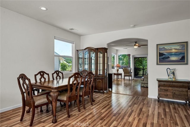 dining room featuring arched walkways, wood finished floors, a ceiling fan, baseboards, and recessed lighting