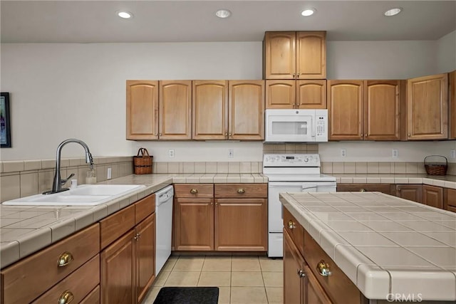 kitchen featuring white appliances, a sink, tile counters, recessed lighting, and light tile patterned floors