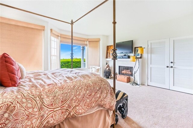 carpeted bedroom featuring a fireplace and a closet