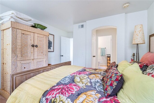 bedroom with arched walkways and connected bathroom