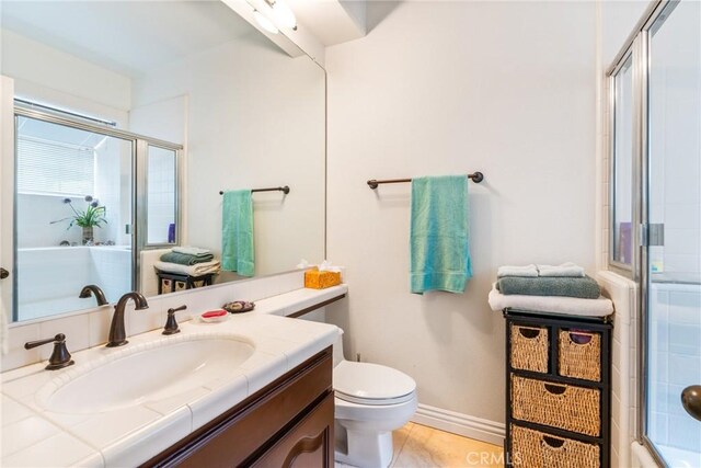 full bath with a shower with door, vanity, toilet, and baseboards