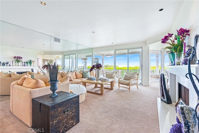 living area featuring light colored carpet and a fireplace with flush hearth