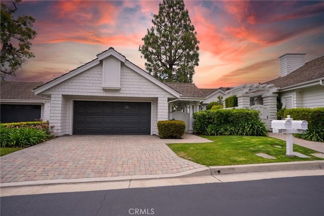 ranch-style house with an attached garage, decorative driveway, and a front lawn