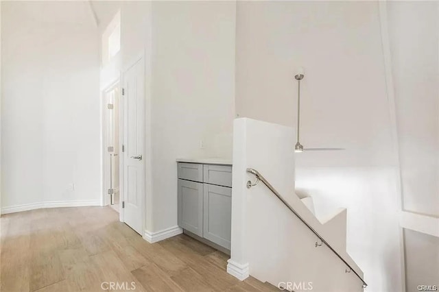 corridor featuring light wood-type flooring and baseboards
