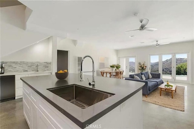 kitchen featuring finished concrete flooring, a sink, white cabinets, ceiling fan, and open floor plan