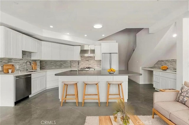 kitchen featuring stainless steel dishwasher, finished concrete flooring, wall chimney exhaust hood, decorative backsplash, and a sink