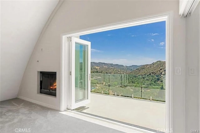 entryway featuring a lit fireplace, carpet, a mountain view, and lofted ceiling