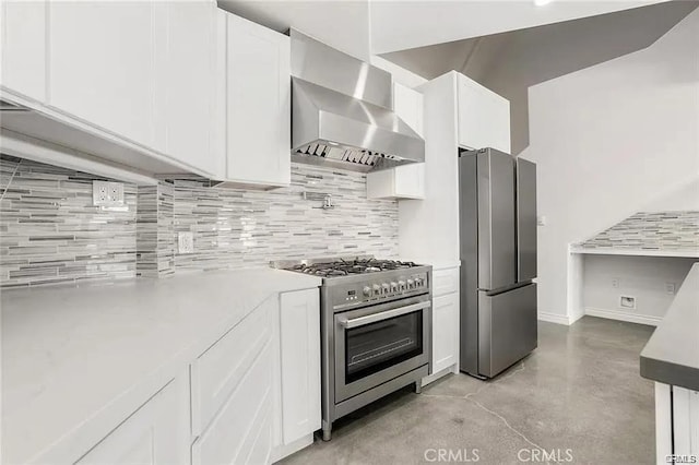 kitchen with stainless steel appliances, wall chimney range hood, white cabinetry, concrete floors, and backsplash