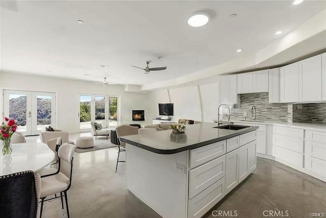 kitchen with finished concrete flooring, a sink, a ceiling fan, tasteful backsplash, and recessed lighting