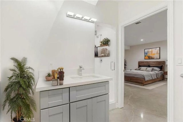 ensuite bathroom featuring concrete flooring and vanity