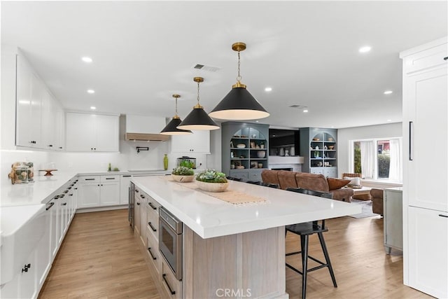20011 Colgate Cir, Huntington Beach, CA 92646 - kitchen with stainless steel microwave, a kitchen island, a breakfast bar area, open floor plan, and light wood finished floors