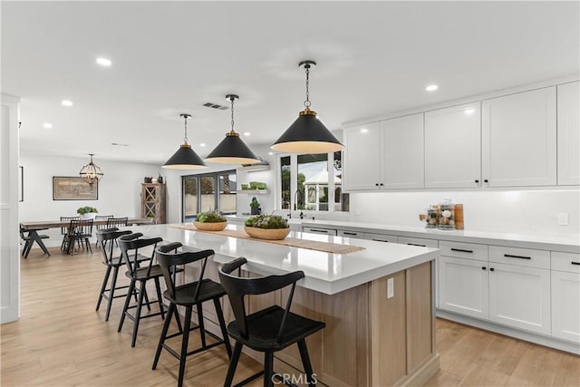 20011 Colgate Cir, Huntington Beach, CA 92646 - kitchen featuring a kitchen island, light countertops, light wood-style floors, recessed lighting, and a kitchen breakfast bar