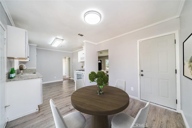 3465 Sepulveda Ave, San Bernardino, CA 92404 - dining space with light wood-style floors, baseboards, and crown molding