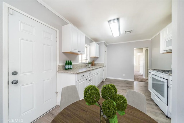 3465 Sepulveda Ave, San Bernardino, CA 92404 - kitchen with white appliances, a sink, white cabinetry, light wood-style flooring, and ornamental molding