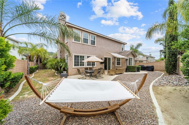 rear view of house with stucco siding, a fenced backyard, and a patio