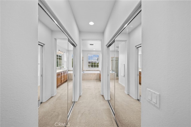 hall featuring light carpet and recessed lighting