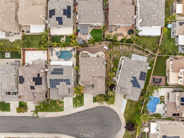 aerial view of property and surrounding area featuring a pool and nearby suburban area