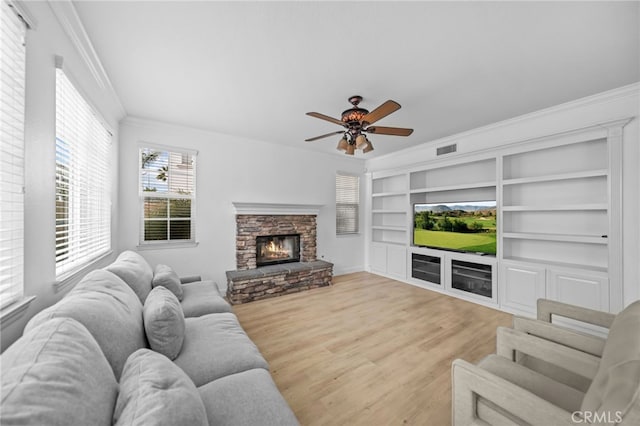 living room featuring crown molding, ceiling fan, built in shelves, wood finished floors, and baseboards