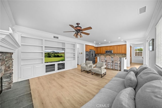 living room featuring recessed lighting, a ceiling fan, ornamental molding, light wood-type flooring, and built in shelves