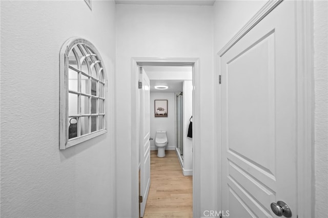 hallway with light wood-style floors and baseboards