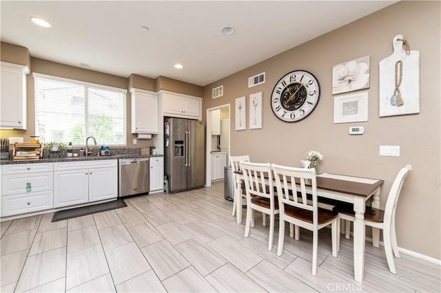 12440 Constellation St, Eastvale, CA 91752 - kitchen with appliances with stainless steel finishes, white cabinets, recessed lighting, a sink, and dark stone counters
