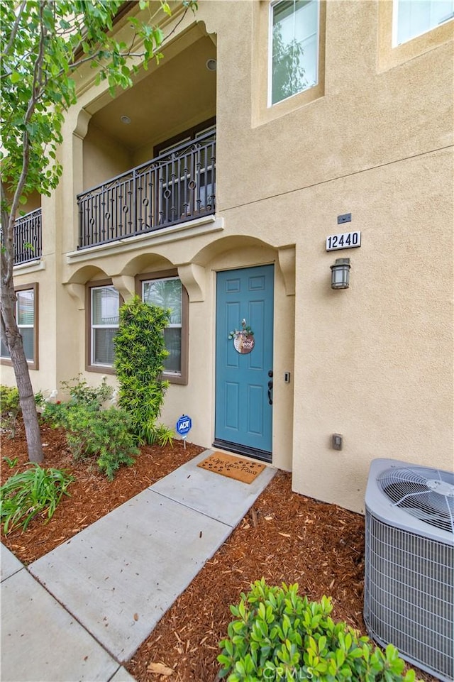 12440 Constellation St, Eastvale, CA 91752 - view of exterior entry with central AC unit, stucco siding, and a balcony